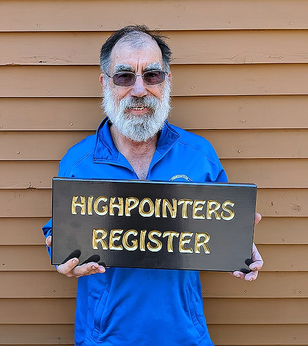 Norman Michaels, a long time supporter of the Highpointers Foundation, holds the sign announcing that there is a Highpointers Register inside the building on top of Mount Washington.
